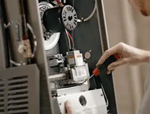 Furnace repair technician inspecting internal components and wiring in Madison, WI
