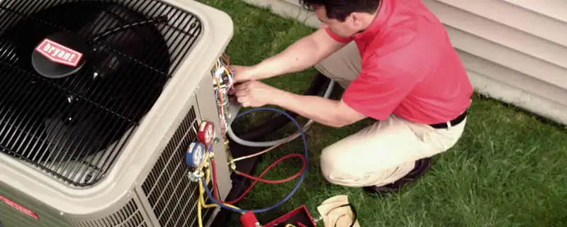 HVAC technician servicing an outdoor air conditioner unit in Madison, WI