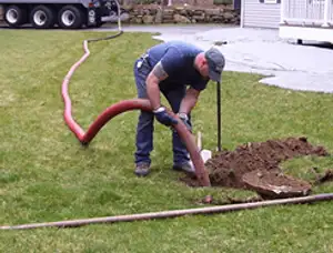 Septic pumping technician servicing a residential septic tank with a vacuum hose in Madison, WI