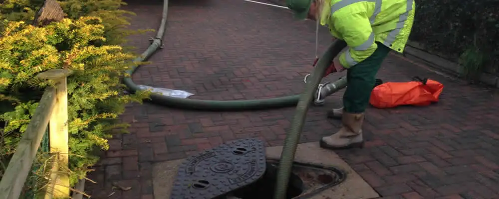 Septic tank cleaning technician servicing a septic tank with a vacuum hose in Madison, WI