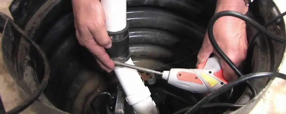 Sump pump installation technician connecting PVC discharge piping in Madison, WI